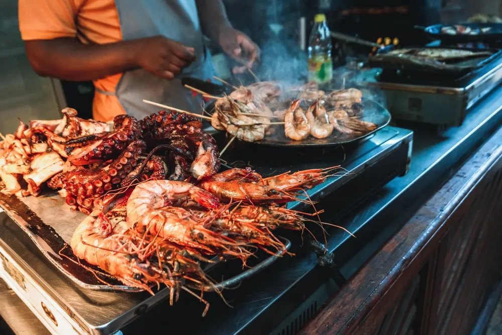 Grilled prawns and octopus on a vendor's hot plate at the Forodhani night food market in Stone Town.